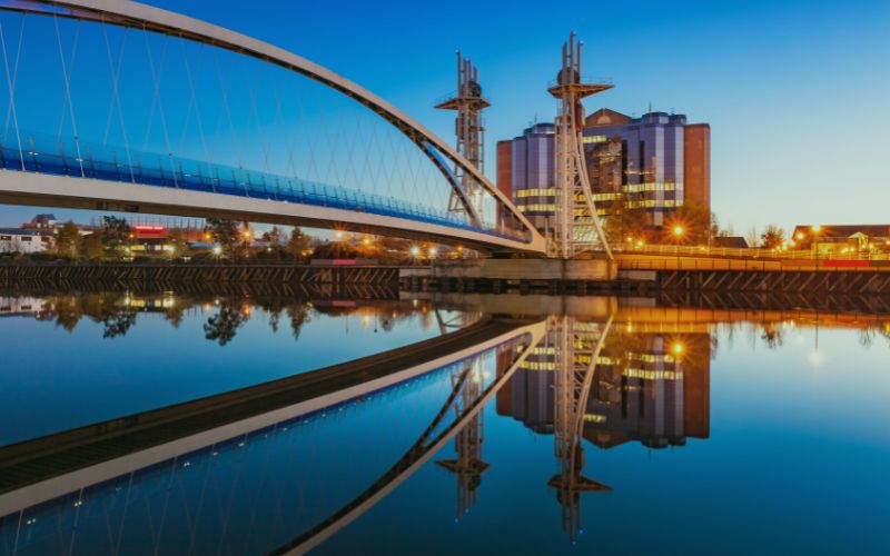 Bridge reflecting on calm water - representing broadband in Manchester